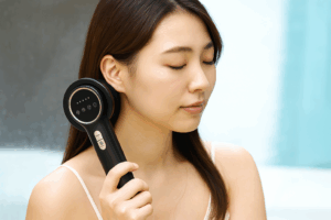 首元にあてた美容機器を操作する女性